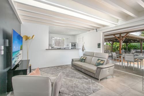 Modern villa living room with beige sofas, kitchen, and open patio in Fort-de-France paradise location