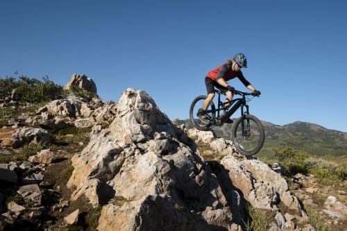 Mountainbiker fährt über felsiges Gelände nahe Verdolivo in Sale Marasino, Italien bei klarem Himmel und Bergen