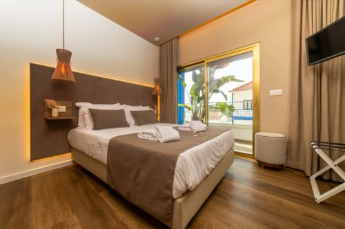 Deluxe double bedroom at Alojamento Costa Alentejana with modern furnishings, balcony view, flat-screen TV, and ocean-facing