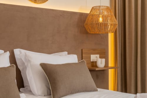 Deluxe double room at Alojamento Costa Alentejana with woven pendant lamp, beige headboard, white pillows, and modern bedside