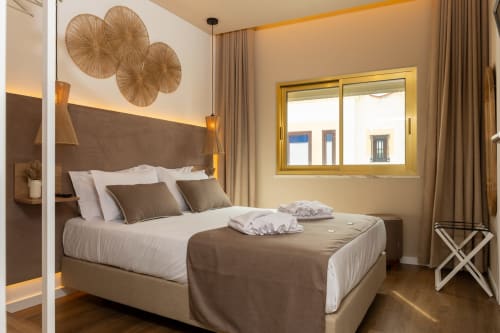 Modern double bedroom at Costa Alentejana in Zambujeira do Mar with brown headboard, white bedding, decorative wall baskets,