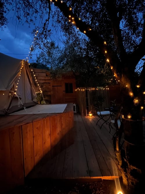 Vue enchantresse du soir de la tente de glamping Tenda Uliveto à l'Agritourisme Stecadò à Dolceacqua, Italie, avec des guirlandes lumineuses chaleureuses et