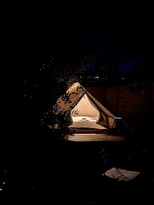 Tente glamping illuminée nichée parmi les oliviers à l'Agritourisme Stecadò à Dolceacqua, avec intérieur douillet et terrasse en bois