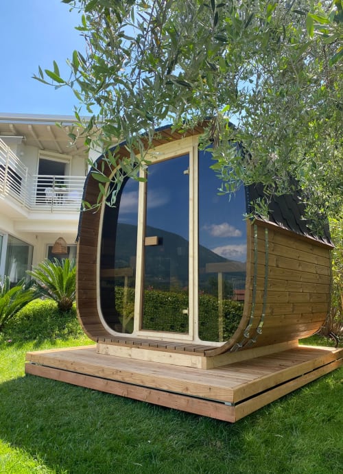 Modern wooden pod cabin with large windows at Verdolivo B&B in Sale Marasino, Italy, nestled in lush greenery with mountain