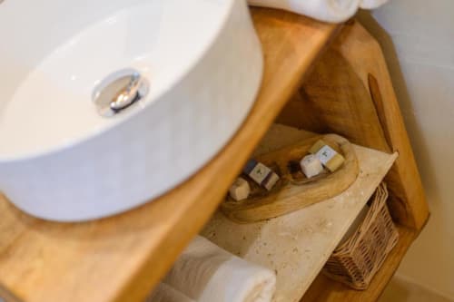 Étagère de salle de bain au gîte Chez Marie et Philippe avec lavabo blanc, organiseur en bois, produits de toilette et serviettes