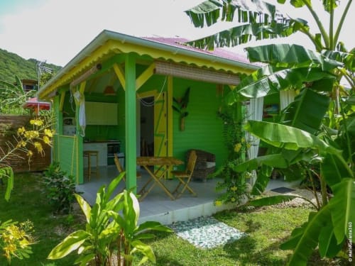 Bungalow vert vif aux finitions jaunes entouré de plantes tropicales à Chez Marie et Philippe en Marie-Galante