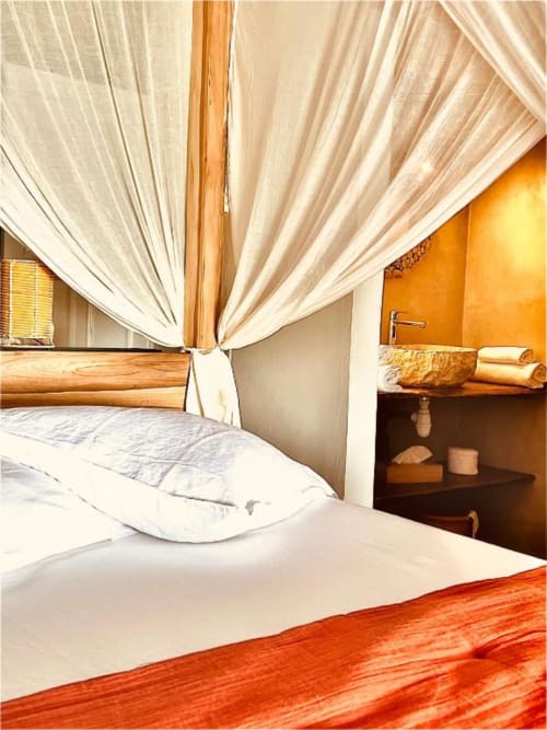 Chambre Touloukaéra chez Marie et Philippe, Marie-Galante, avec lit à baldaquin, draps blancs et terrasse vue mer.