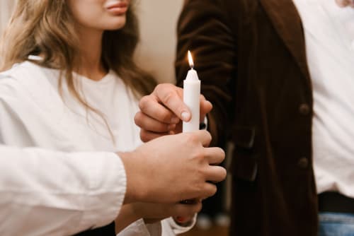 Two people holding a lit white candle together at Paradise Location hotel in Fort-de-France