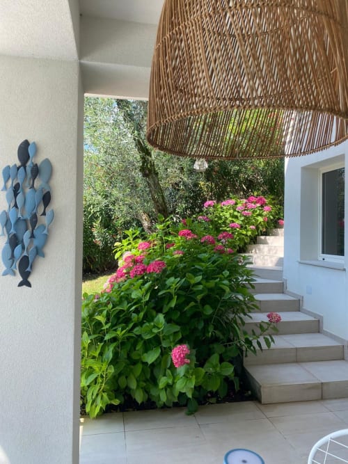 Verdolivo B&B patio with pink flowers, woven shade structure, and blue fish wall art in Sale Marasino