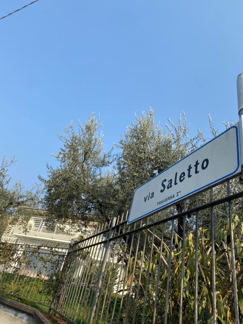 Via Saletto street sign at Verdolivo B&B in Sale Marasino, Italy with olive trees and blue sky