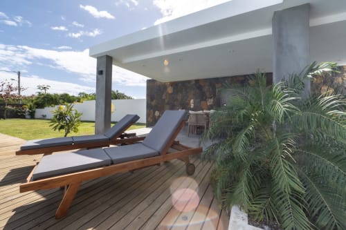 Élégant espace de détente au bord de la piscine de La Villa Boz avec transats en bois et plantes tropicales à Saint Philbert de Bouaine