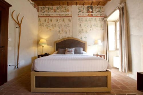 Deluxe bedroom at Hotel San Giovanni Resort in Saluzzo with wooden bed, white linens, and garden views