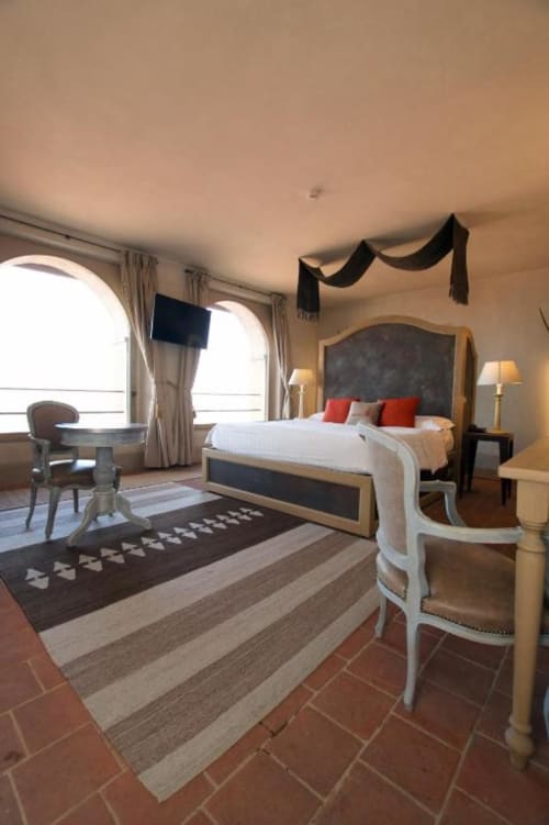 Elegante suite junior presso Hotel San Giovanni Resort con vista montagna, letto con cuscini rossi, finestre ad arco