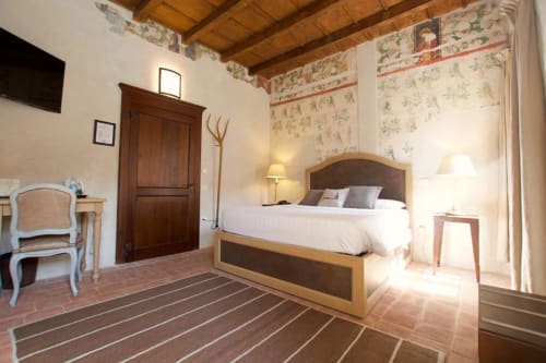 Camera deluxe dell'Hotel San Giovanni Resort a Saluzzo con letto in legno, pavimento in terracotta e vista sul giardino