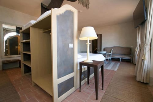 Junior Suite at Hotel San Giovanni Resort in Saluzzo with bed, sofa, lamp, and wooden wardrobe furniture