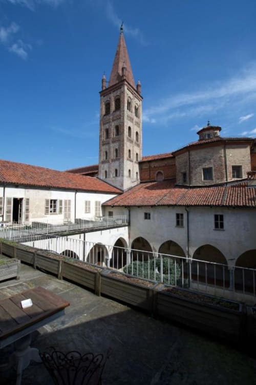 Hotel San Giovanni Resort courtyard in Saluzzo with bell tower and terracotta roofed buildings