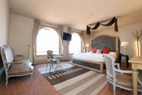 Elegant Junior Suite at Hotel San Giovanni Resort in Saluzzo with mountain views, featuring a wood-framed bed, sitting area,