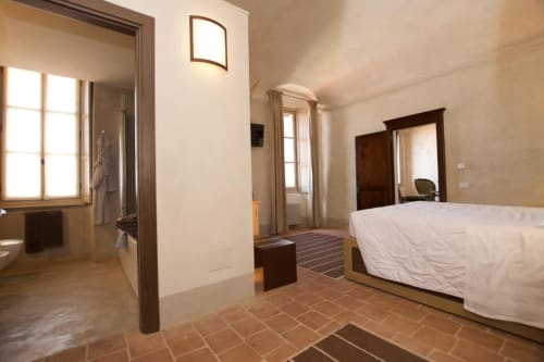 Superior Double Room at Hotel San Giovanni Resort in Saluzzo with white bed, terracotta floors, and garden views