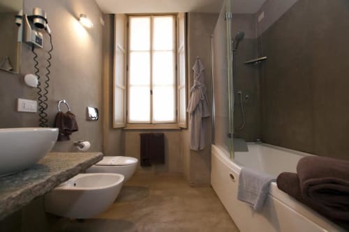 Modern bathroom in Hotel San Giovanni Resort Superior Room with dual sinks, shower enclosure, and window overlooking garden
