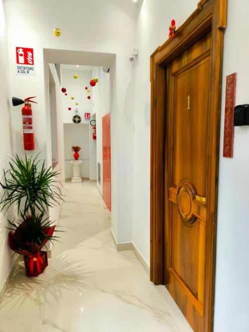 Elegante corridoio dell'hotel I Migliori Artisti Napoli con porta in legno, elementi decorativi rossi e atmosfera natalizia