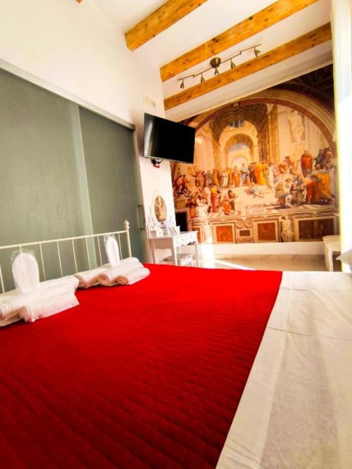 Camera doppia superior a I Migliori Artisti B&B a Napoli con biancheria rossa, murale con vista città, travi in legno e TV a schermo piatto