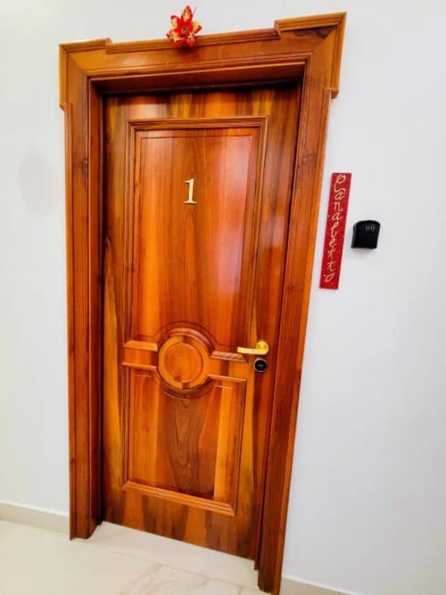 Porta in legno numero 1 presso il lussuoso B&B I Migliori Artisti a Napoli con ornamento rosso decorativo e pergamene cinesi
