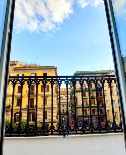 Vista dal balcone di colorati edifici napoletani attraverso la ringhiera in ferro ornato a I Migliori Artisti, Napoli