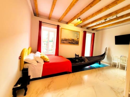 Camera Tripla di Lusso a I Migliori Artisti a Napoli con letto rosso, decori gondola, travi a vista e vista sulla città