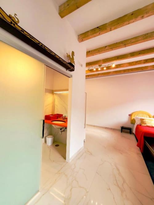 Lussuosa camera tripla presso I Migliori Artisti Napoli con soffitto a travi in legno, letti rossi, pavimenti in marmo, bagno privato e vista città