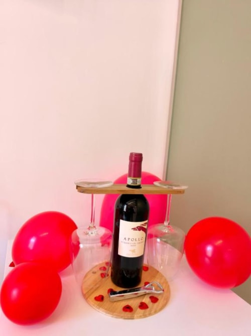 Allestimento romantico con palloncini rossi, bottiglia di vino, bicchieri e decorazioni a cuore in una lussuosa camera presso I Migliori Artisti