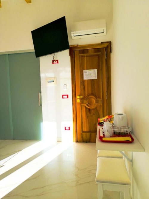 Camera moderna presso I Migliori Artisti a Napoli con TV a schermo piatto, porta in legno, pavimenti in marmo e unità di climatizzazione