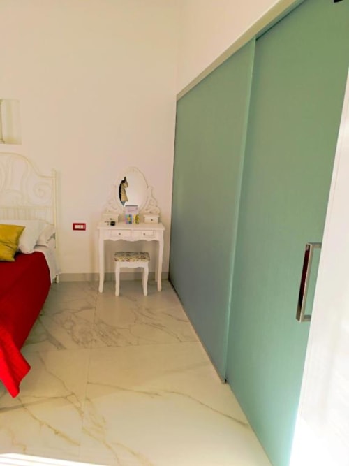 Camera doppia deluxe all'I Migliori Artisti Napoli con pavimenti in marmo, mobile bianco, armadio verde e biancheria rossa