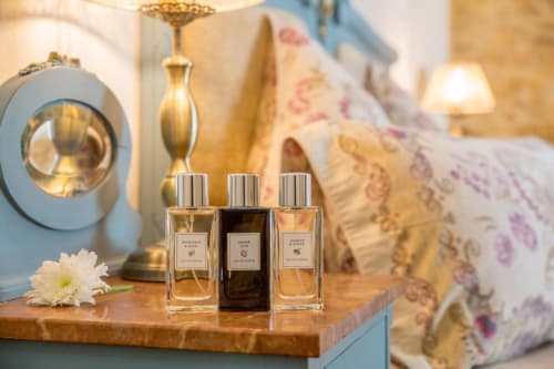 Botellas de perfume de lujo exhibidas en mesa de madera en la habitación de La Vista Medina Stays con detalles en latón