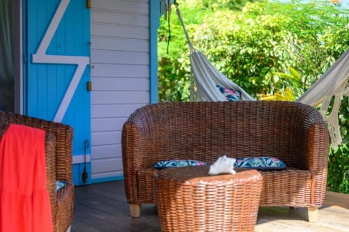 Salon en rotin sur la terrasse de la maison d'hôtes Chez Marie et Philippe à Marie-Galante, avec vue sur le jardin