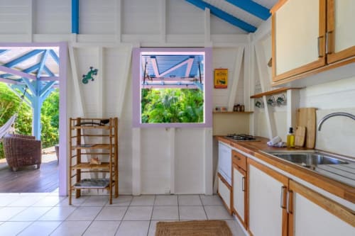 Cuisine lumineuse du gîte Ti'Kaz Cannelle chez Marie et Philippe, Marie-Galante, avec meubles en bois et vue sur le jardin