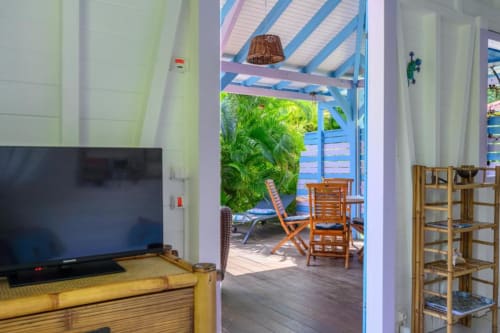 Intérieur du cottage Ti'Kaz Cannelle avec télévision, ouvert sur une terrasse avec transats et vue sur la piscine chez Marie et Philippe,