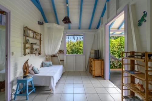 Chambre lumineuse de la villa Ti'Kaz Cannelle chez Marie et Philippe à Marie-Galante, avec lits jumeaux, murs blancs et plafond bleu