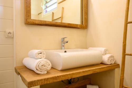 Lavabo de salle de bain avec serviettes blanches roulées sur un comptoir en bois à la villa Chez Marie et Philippe en Guadeloupe