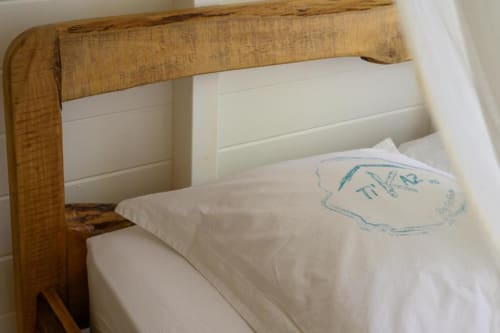 Lit à tête de lit en bois avec draps blancs et détails bleus à la villa Ti'Kaz Vanille en Guadeloupe