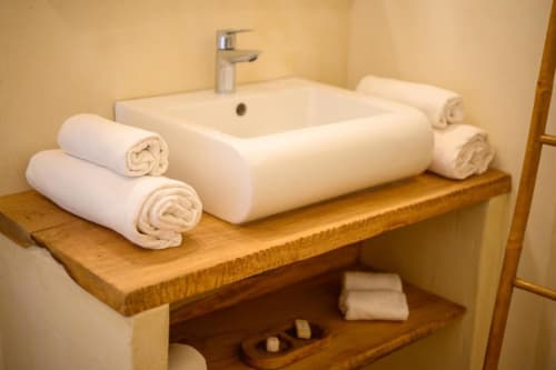 Lavabo de salle de bain moderne avec serviettes blanches roulées sur une étagère en bois à la villa Chez Marie et Philippe en Guadeloupe
