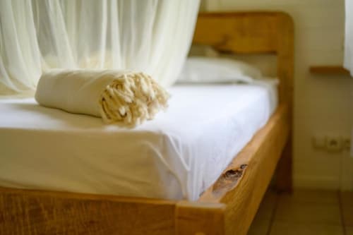 Lit en bois avec draps blancs et couverture crème à la villa Ti'Kaz Vanille, Chez Marie et Philippe, Marie-Galante