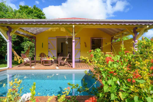 Charmante maison jaune vif au bord de la piscine avec accents violets, transats et jardins fleuris à Chez Marie et Philippe,