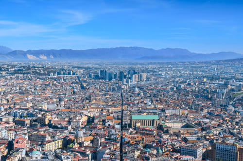 Aerial view of Naples with mountains, historic architecture, and cityscape from I Migliori Artisti BnB