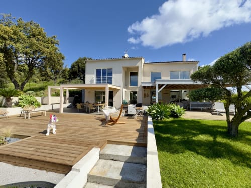 Villa SoleMare à Alata avec terrasse en bois spacieuse, architecture blanche moderne et jardins paysagés sous ciel bleu