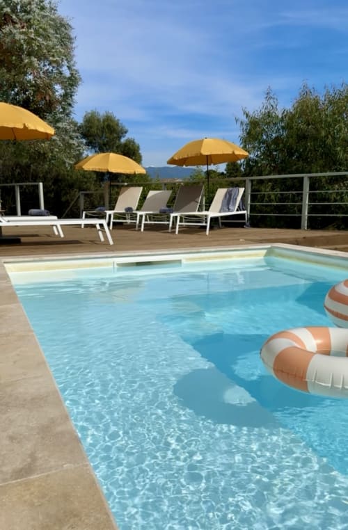 Piscine de l'hôtel SoleMare à Alata, France avec chaises longues, parasols jaunes et vue sur les montagnes
