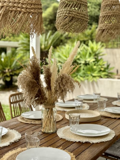 Table de salle à manger SoleMare en plein air à Alata avec centre de table en herbes de la pampa, sets de table tissés et décoration naturelle