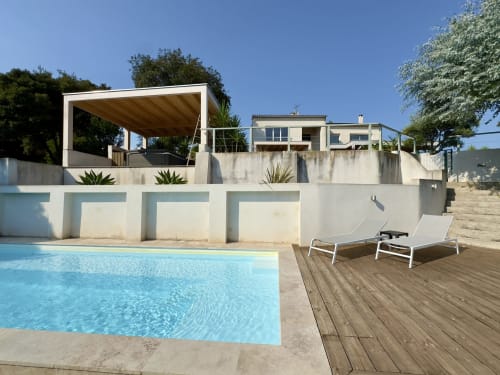 Terrasse piscine de l'hôtel SoleMare avec transats, pergola moderne et vue sur mer à Alata, Corse