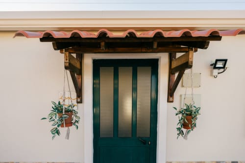 Casa Laranjeira villa entrance at Tree House, Sesimbra, with green door, wooden pergola, and hanging plants