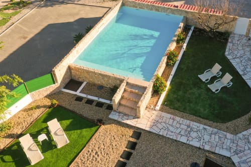 Aerial view of Casa Laranjeira villa in Sesimbra with turquoise pool, manicured garden, lounge chairs, and patio area