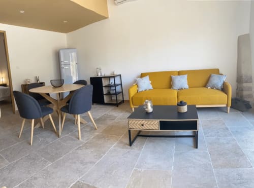 Modern living room with yellow sofa, dining table, and black coffee table in Mas St André cottage, Provence